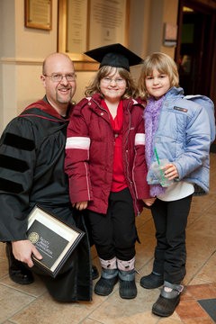 honored faculty member smiles for photo with two children